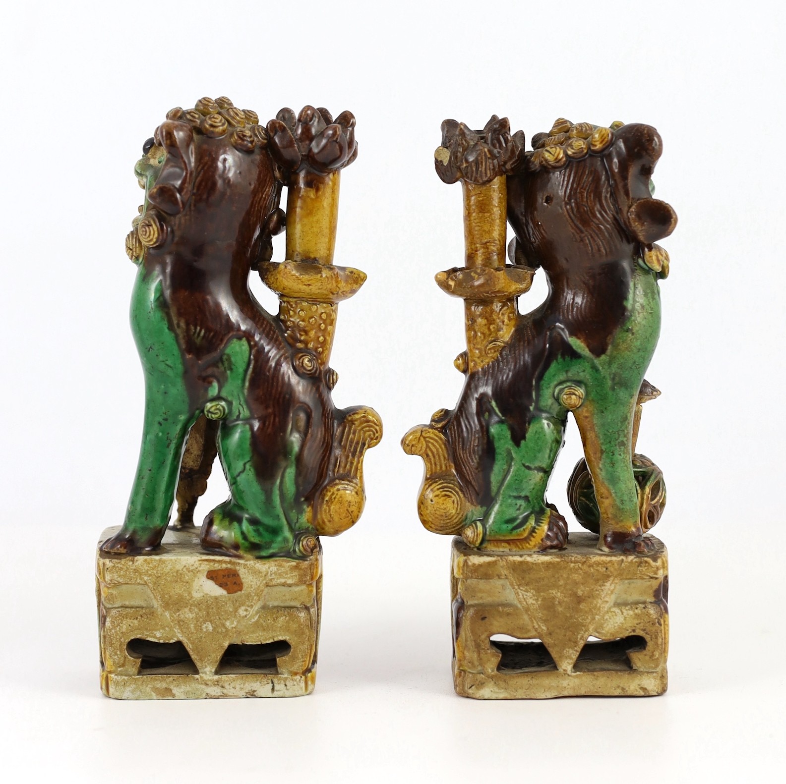 A pair of Chinese sancai-glazed biscuit Buddhist lion joss stick holders, Kangxi period, 15.5 and 16cm high, some restoration
